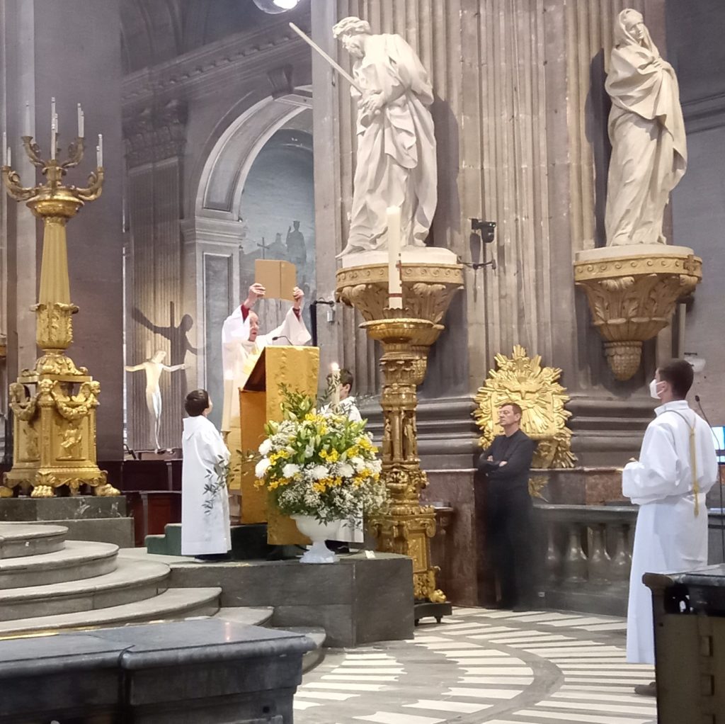 les servants de messe tiennent les cierges autour du diacre.